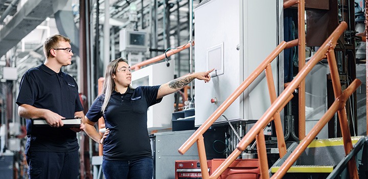 Chem-Trend production workers pointing to digitalized chemical manufacturing screen. 